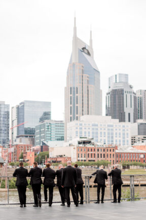 Groomsmen Looking Out at Downtown Nashville on Riverfront Patio {{brizy_dc_image_alt imageSrc=