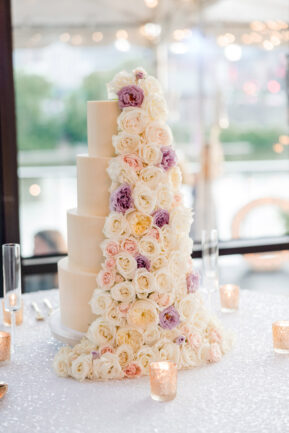 Four tier wedding cake with ivory and purple florals up one side {{brizy_dc_image_alt imageSrc=