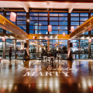 A birthday party set in our private event venue with paper lanterns and grand piano in the Cumberland space with a gobo light that reads {{brizy_dc_image_alt imageSrc=