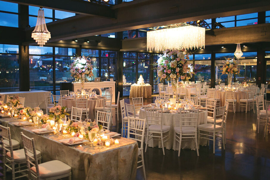 Glam pink wedding reception with elegant chandeliers, white chairs, baby pink and gold table linens at The Bridge Building, downtown Nashville wedding venue