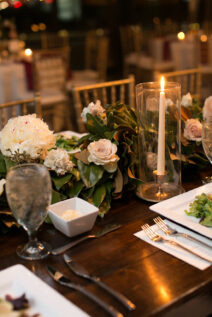 Table decor with magnolia leaves and pink and ivory flowers with taper candles for romantic winter wedding at The Bridge Building, downtown Nashville wedding venue