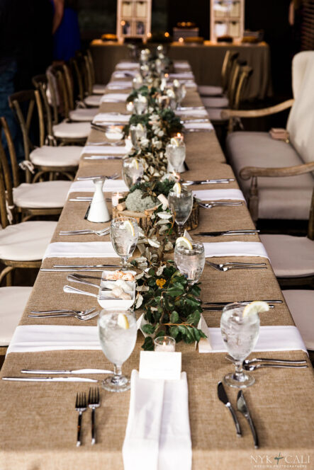 Farmhouse head table with burlap linens and dried greenery runner for nautical themed rehearsal dinner {{brizy_dc_image_alt imageSrc=
