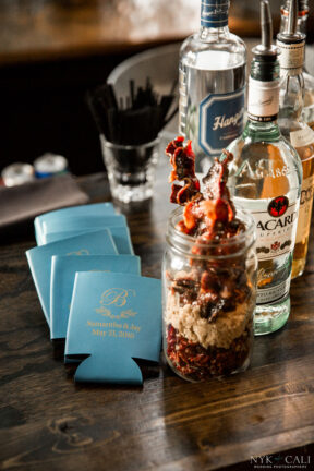 Candied bacon on the bar next to custom koozies {{brizy_dc_image_alt imageSrc=